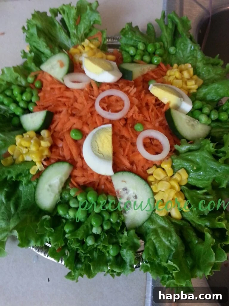 Freshly prepared Cameroon lettuce salad with vibrant green leaves, shredded carrots, cucumber slices, sweet corn, green peas, and hard-boiled egg, ready for dressing.