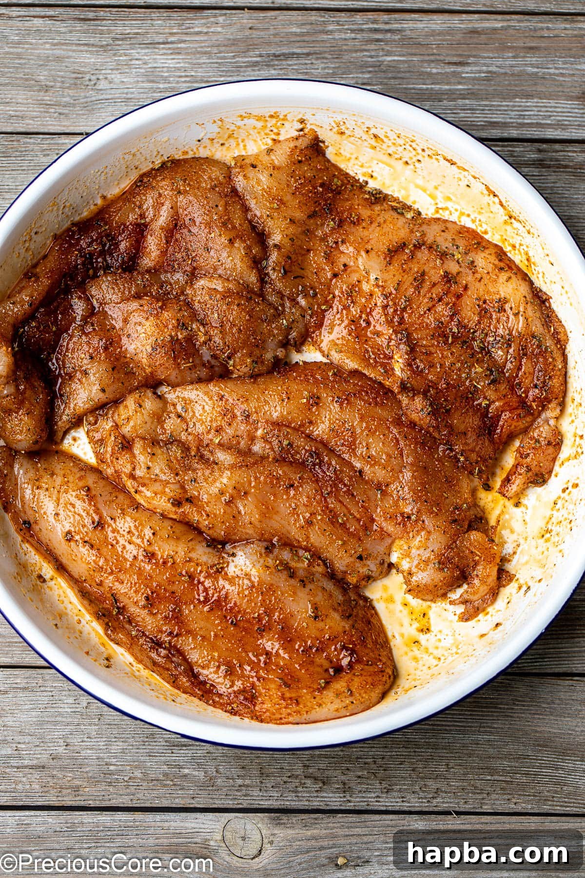 Tender Baked Chicken Cutlets 7 Thin chicken breasts in a white bowl, generously coated with a vibrant spice blend, ready for baking.
