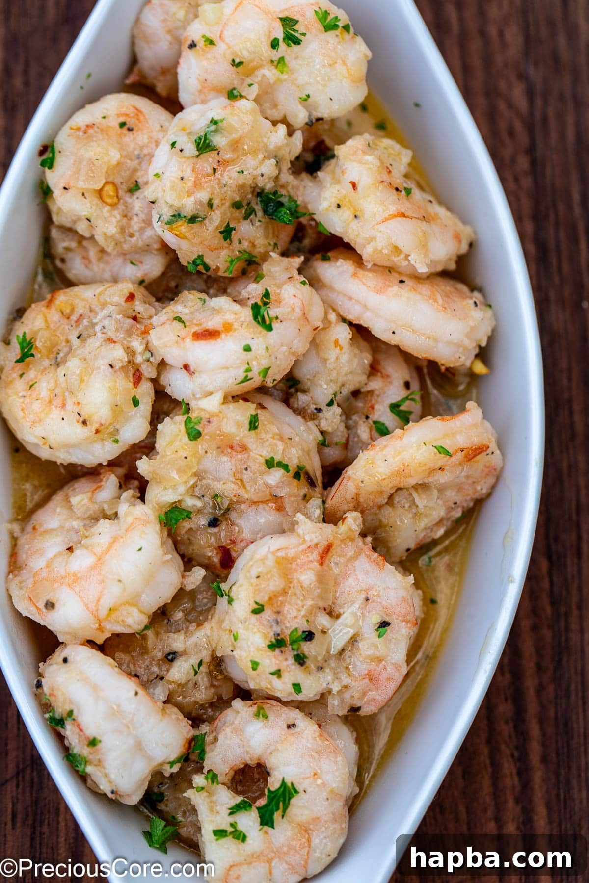 A beautifully plated serving of shrimp in white wine sauce, garnished with fresh herbs.