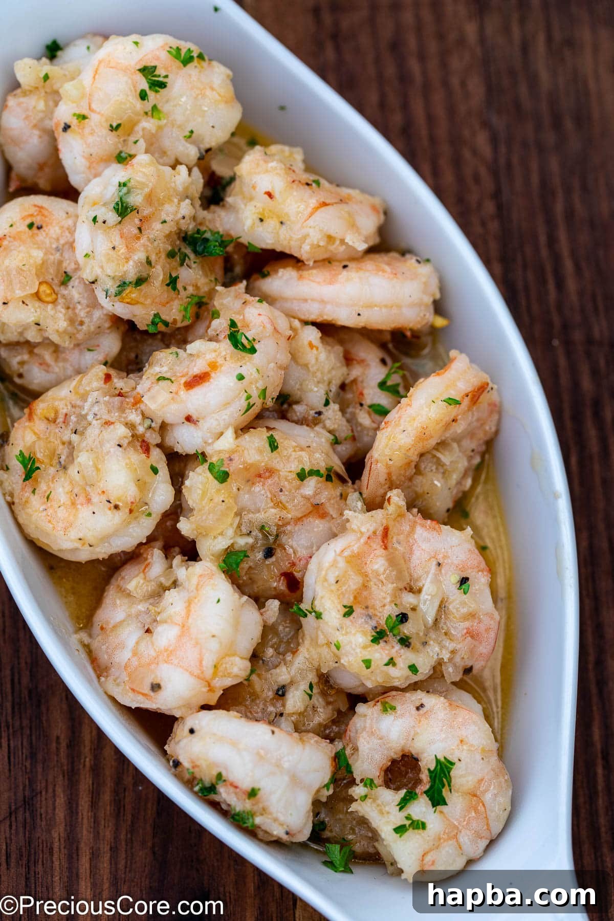 Shrimp in white wine sauce served in a small elegant white bowl, ready to be enjoyed.