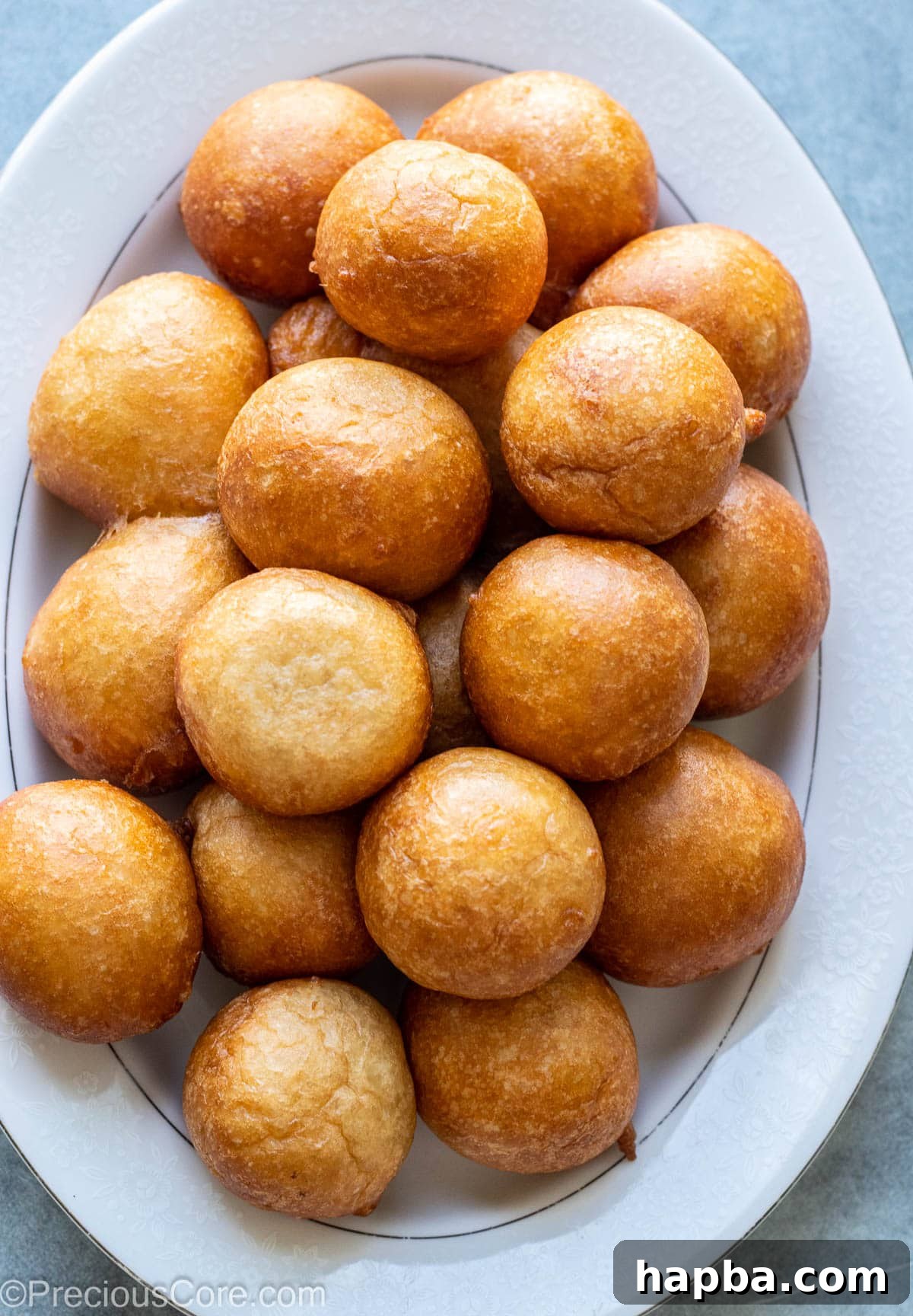 Golden brown Puff Puff piled on a white tray, showcasing their fluffy texture.
