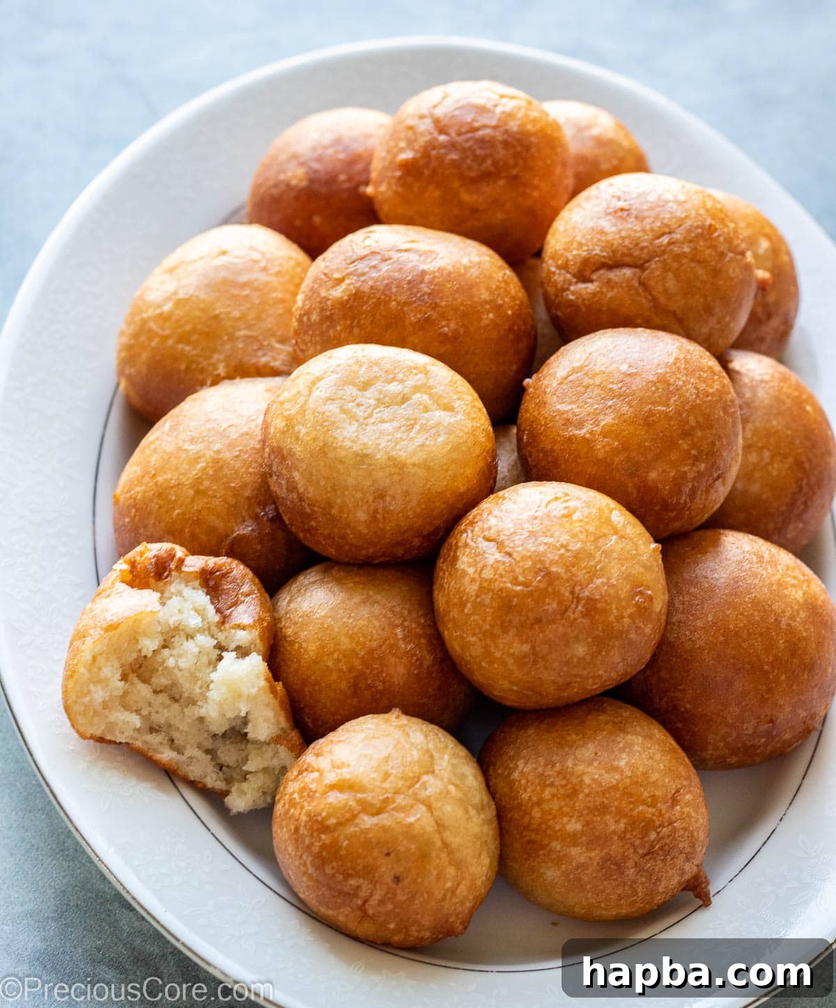A selection of Puff Puff on a tray, one cut open to reveal its airy, fluffy interior.