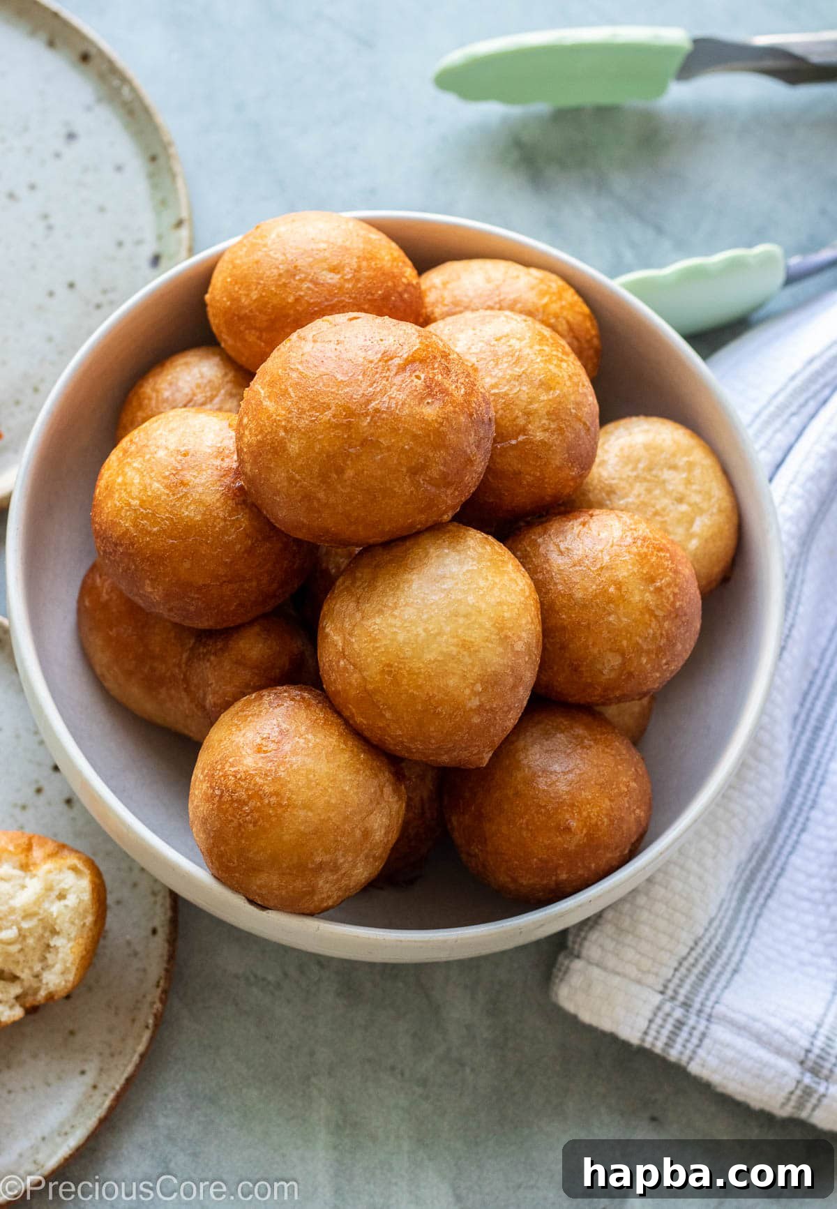 A large bowl overflowing with perfectly fried, golden brown Puff Puff.