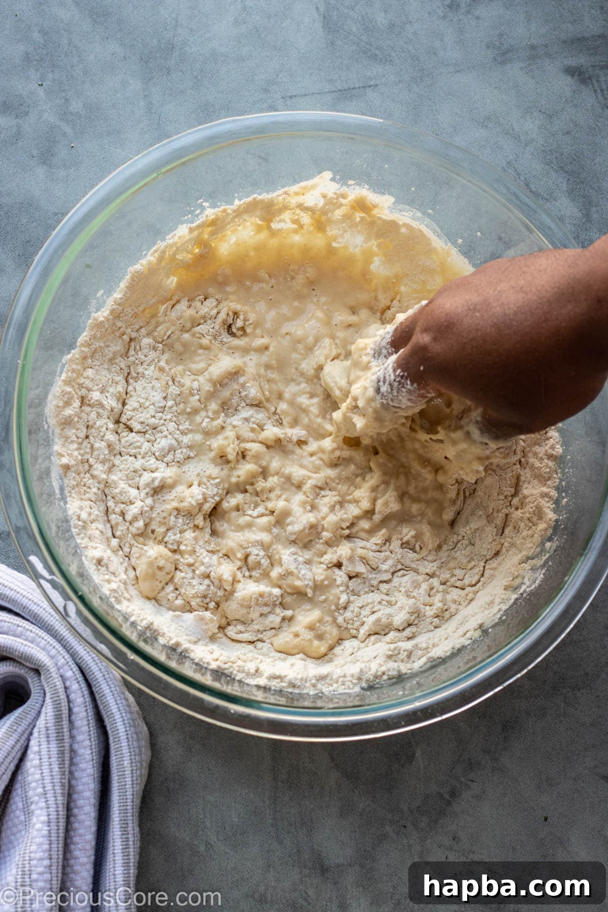 A hand mixing Puff Puff batter in a large bowl with a wooden spoon.