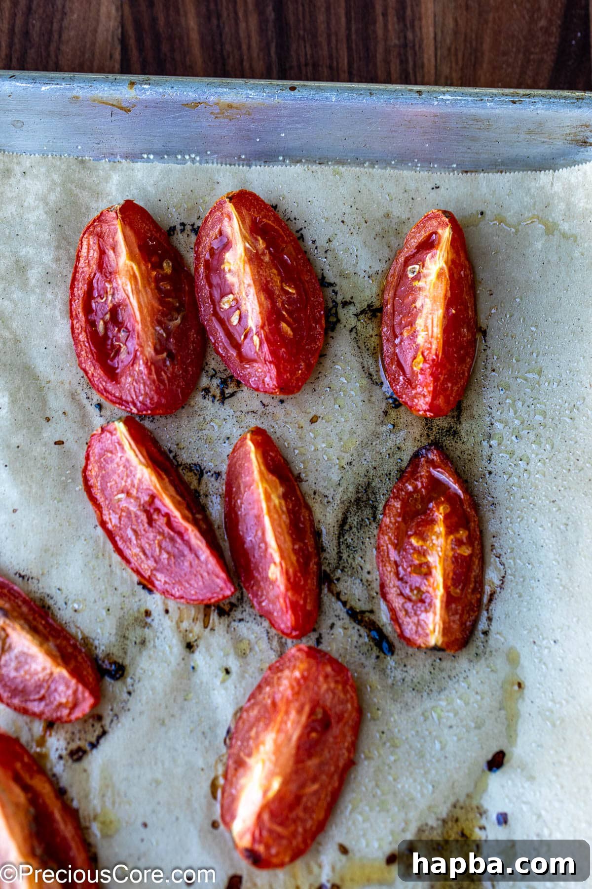 Roasted tomatoes on a baking sheet lined with parchment paper.