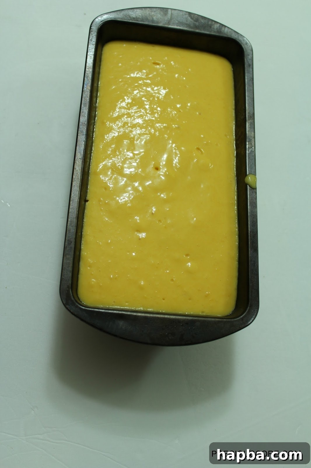 Loaf pan filled with mango coconut sorbet mixture, covered and ready for freezing