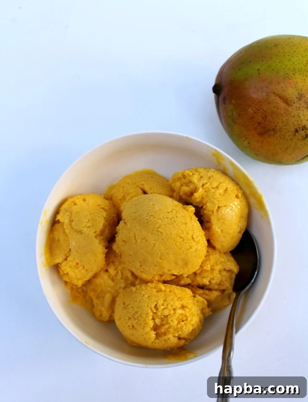 A vibrant scoop of homemade mango sorbet in a glass bowl