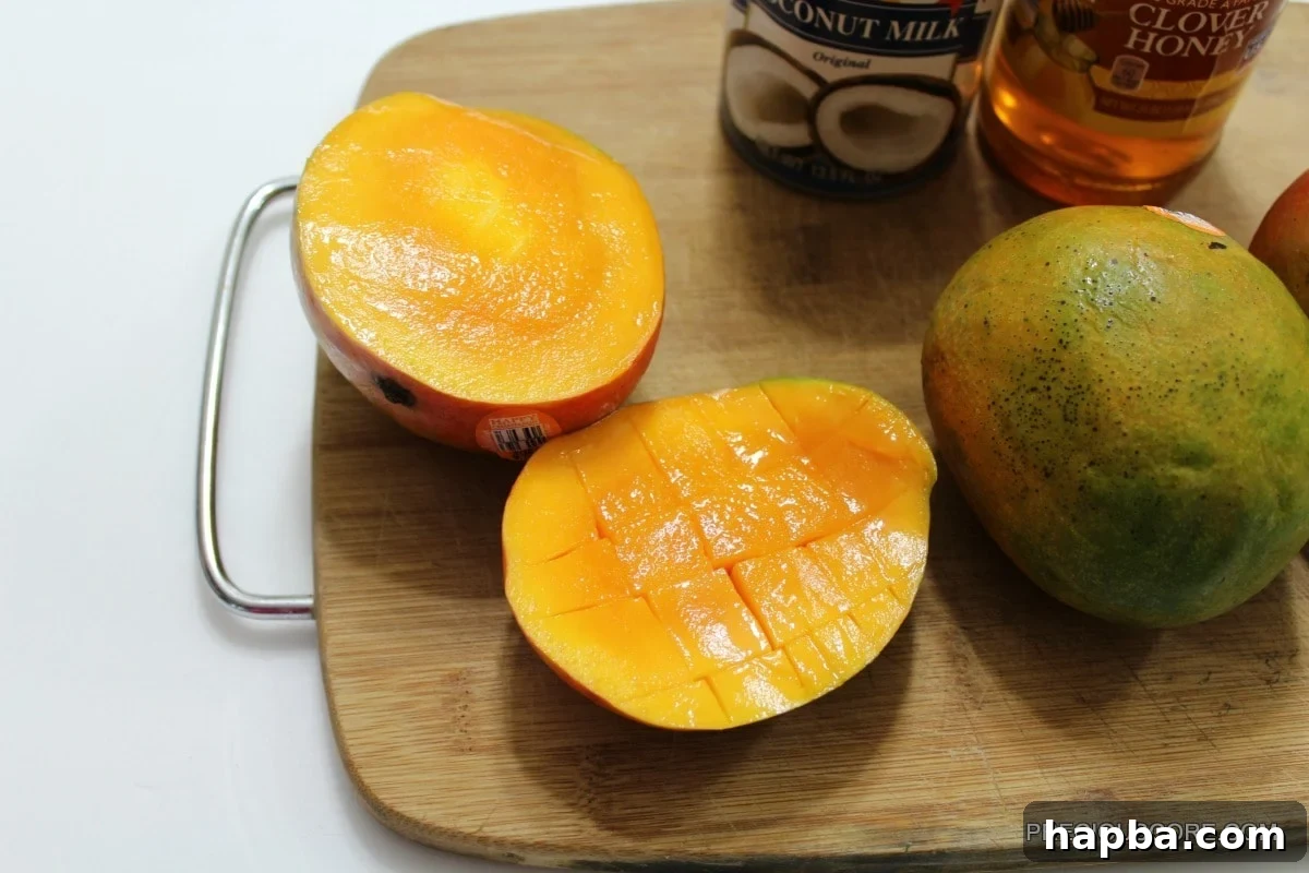 Chef's hand scoring a mango half into a grid pattern for dicing