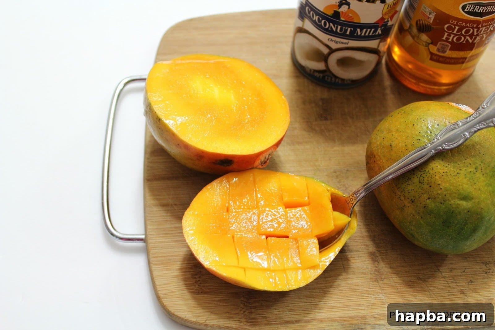 A spoon scooping out diced mango from its skin, ready for a taste