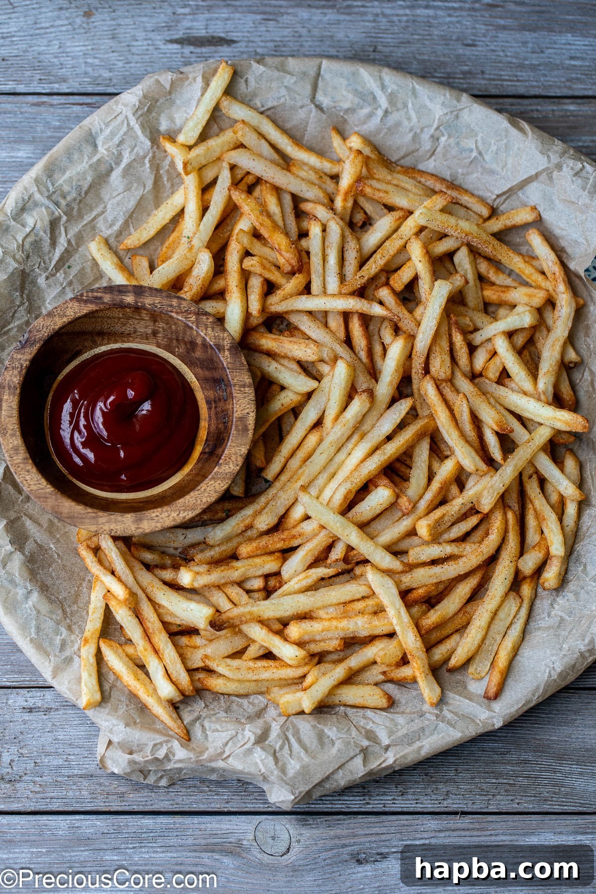 Perfectly air-fried French fries served on a round platter, with a small bowl of ketchup for dipping.