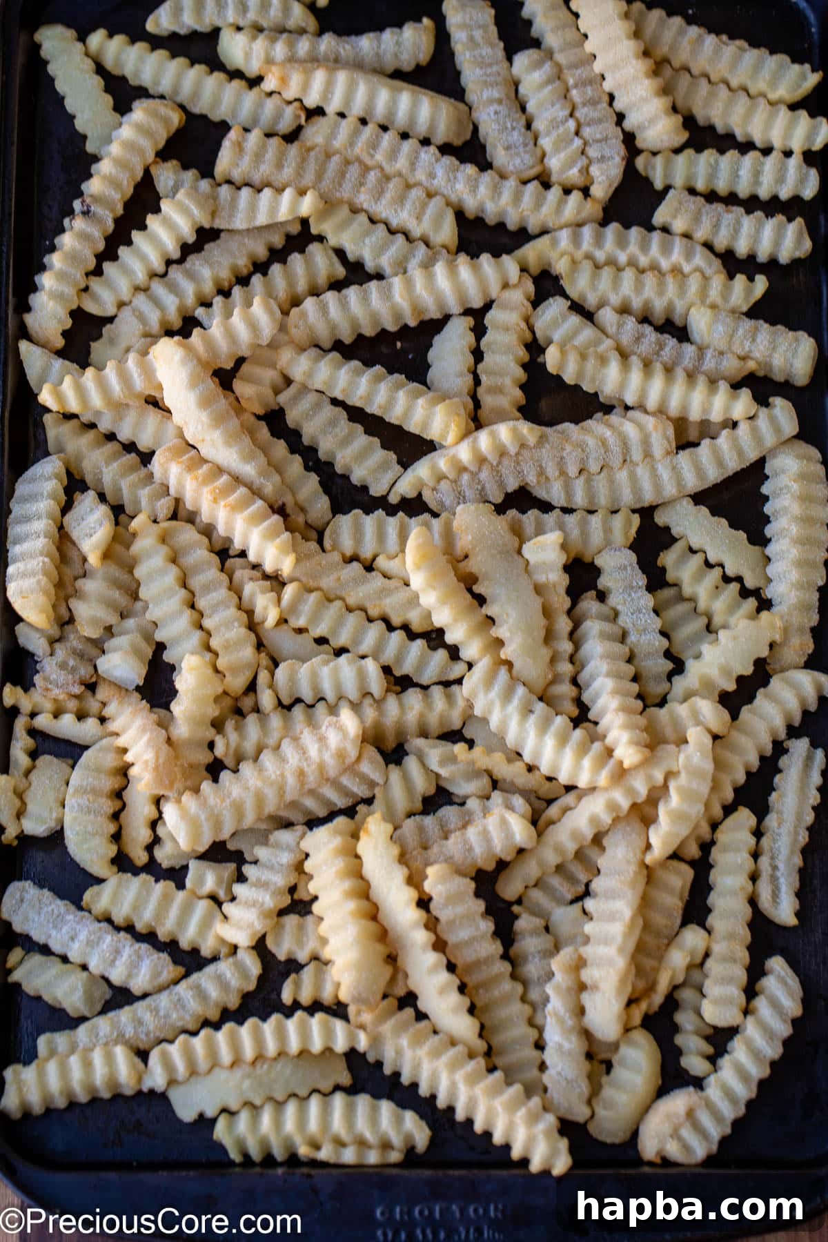 Frozen French fries spread on a sheet pan, ready for cooking.