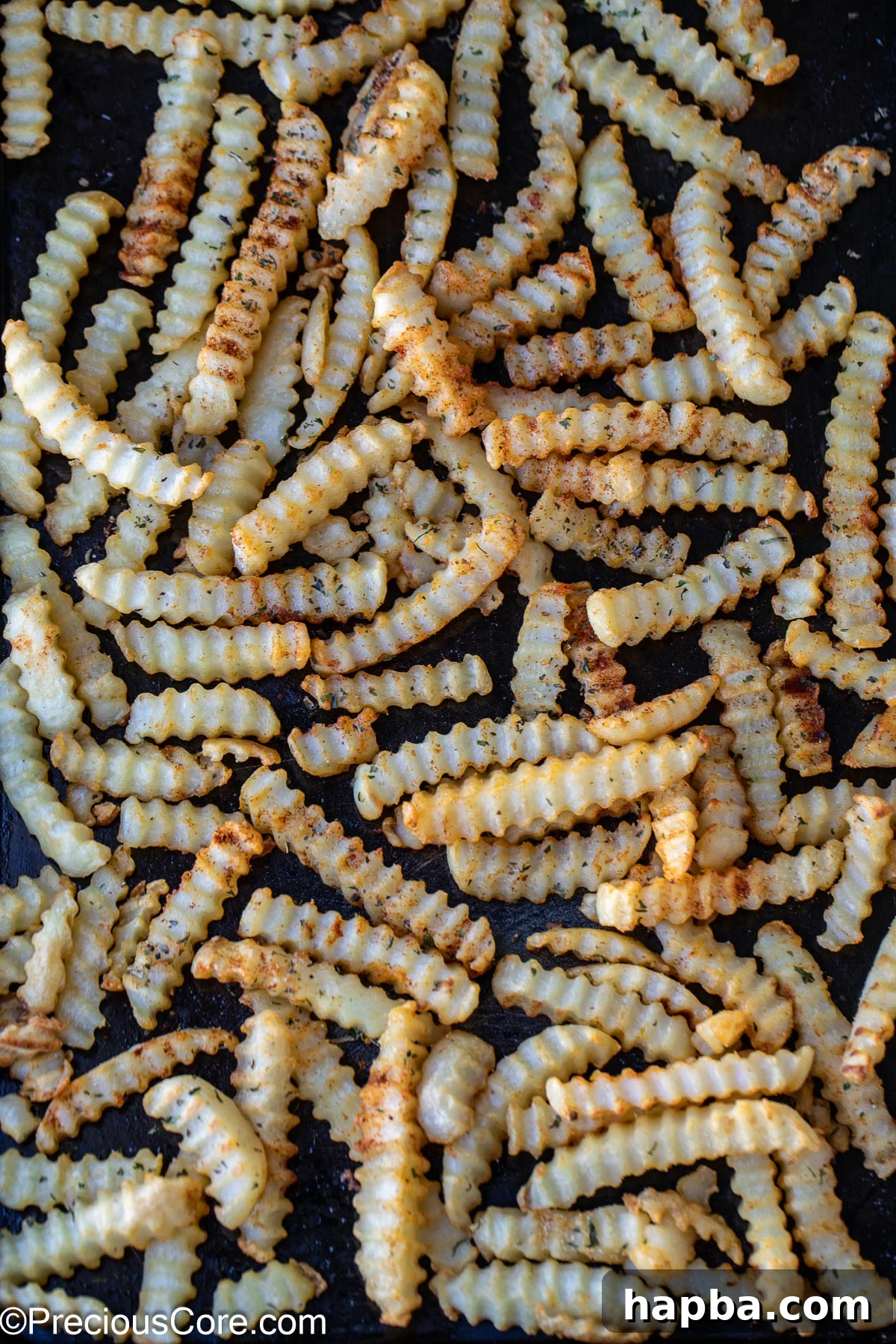 Seasoned crinkle-cut fries arranged on a sheet pan, ready for the oven.