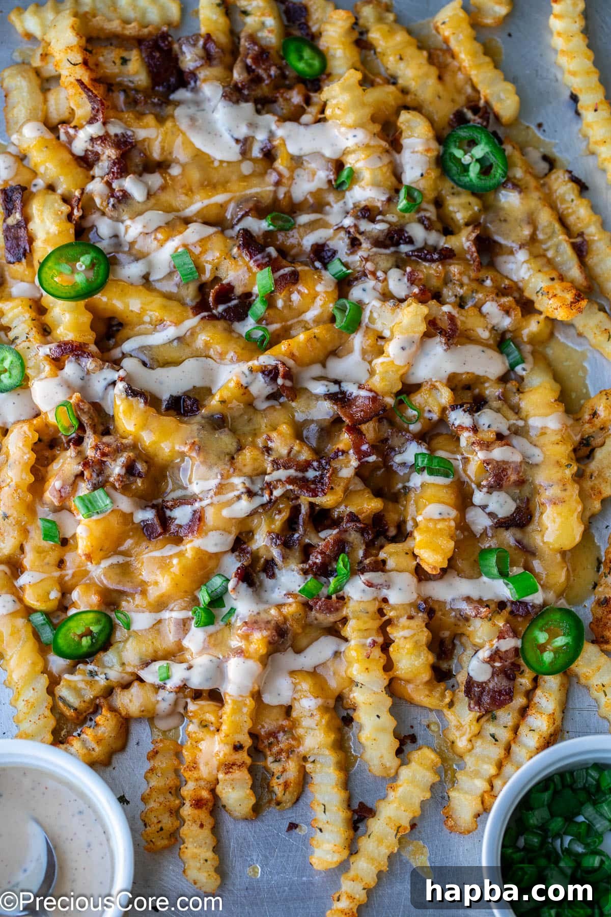 Loaded French Fries on a sheet pan, garnished with sliced green onions and fresh jalapeños.