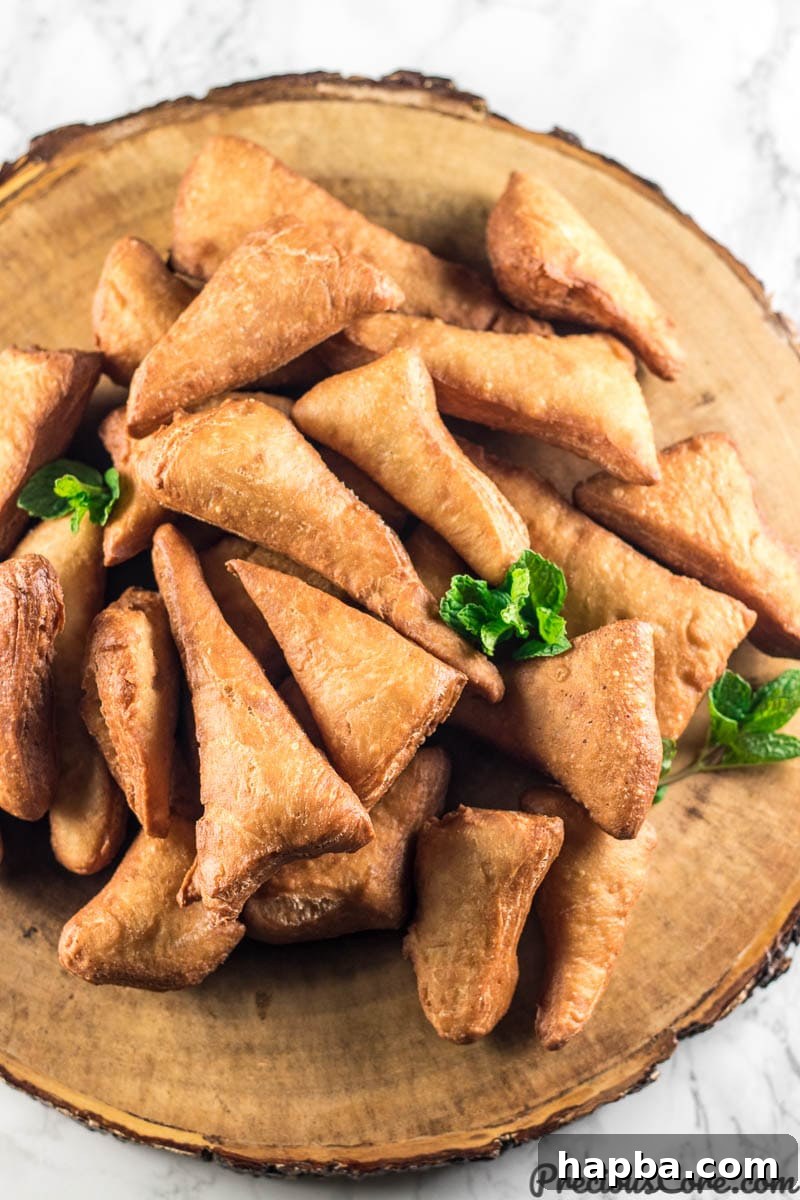 A rustic brown serving platter piled high with golden-brown Mandazi doughnuts, inviting you to enjoy these East African delights.
