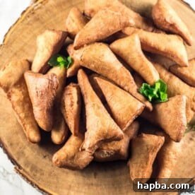 A close-up view of freshly made Mandazi, highlighting their characteristic triangular shape and golden-brown exterior, often enjoyed in Kenya, Tanzania, and Uganda.