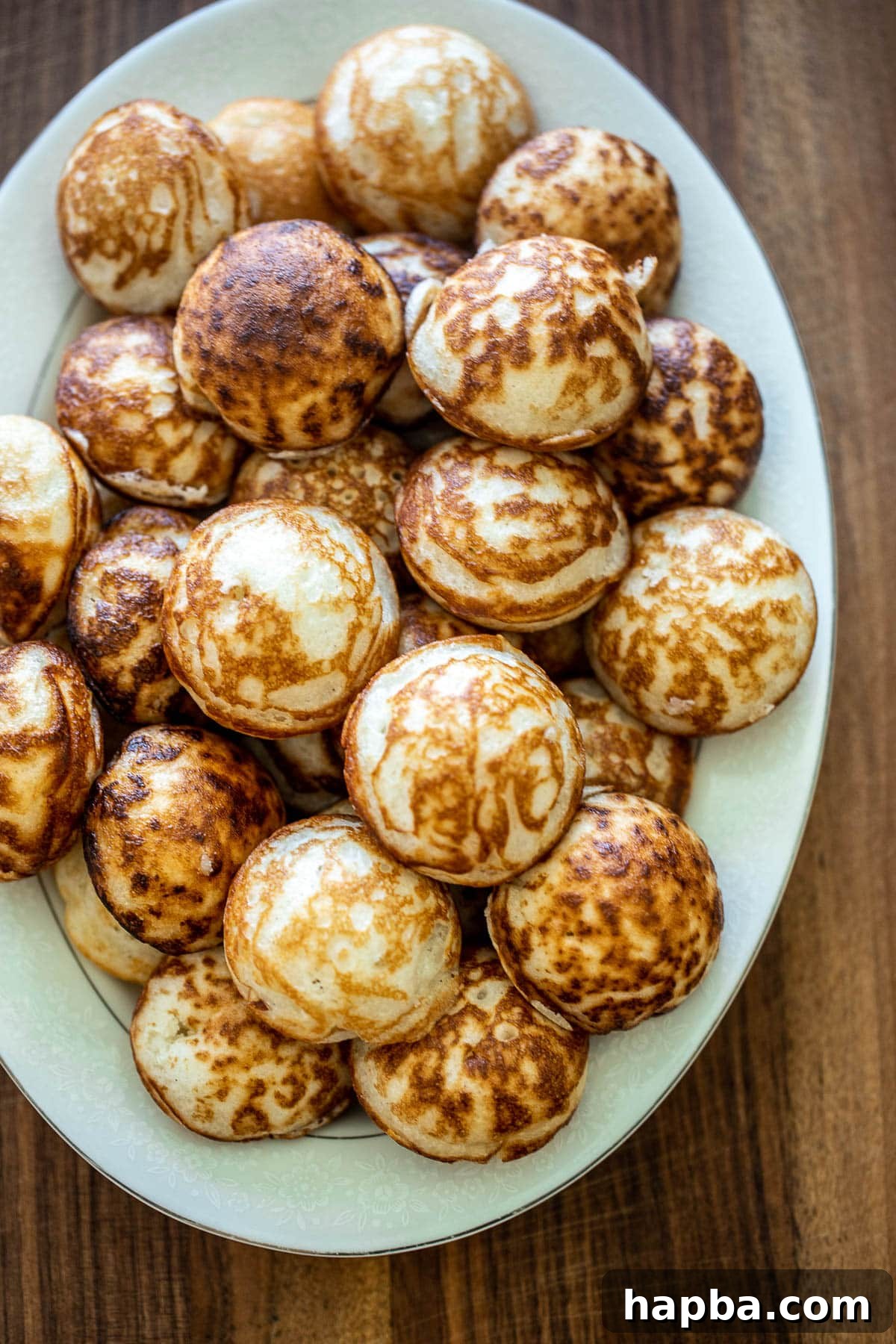 A pristine white tray displaying an array of perfectly cooked Vitumbua, their golden edges and soft centers inviting you to indulge in these East African coconut rice pancakes.