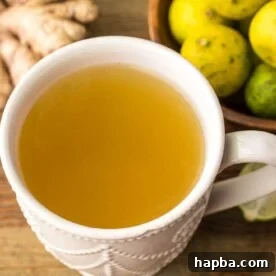 A mug of refreshing fresh ginger drink, elegantly presented with a side of ginger root and key limes.