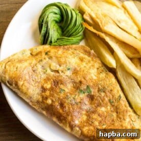 Close-up of a serving of breakfast fried potatoes and eggs, showcasing the crispy fries and savory omelette.