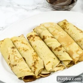 A plate of neatly rolled Cameroonian pancakes, highlighting their soft and inviting appearance.