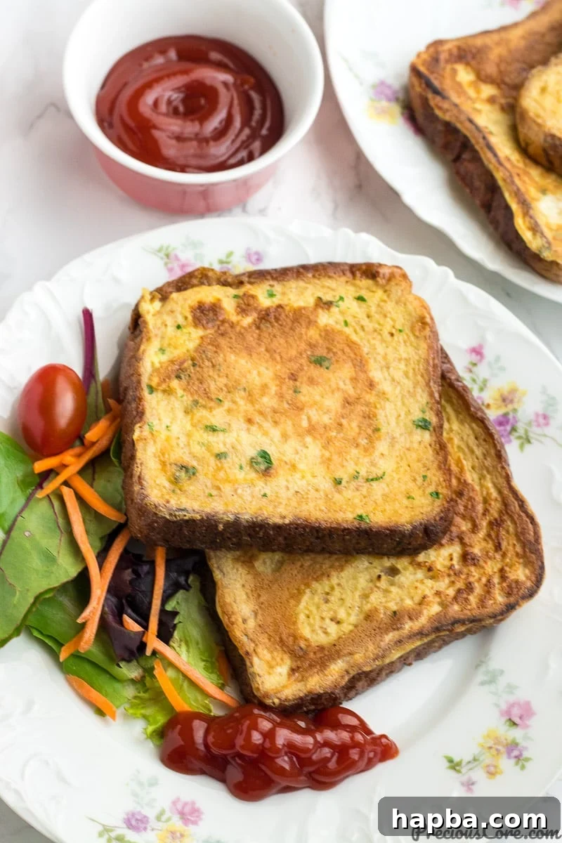 Savory French Toast slices arranged on a plate, accompanied by a side of ketchup and a vibrant mix of fresh vegetables.