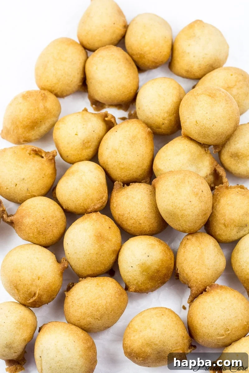 A collection of freshly fried Cameroonian drop doughnuts resting on white parchment paper, ready to be enjoyed.