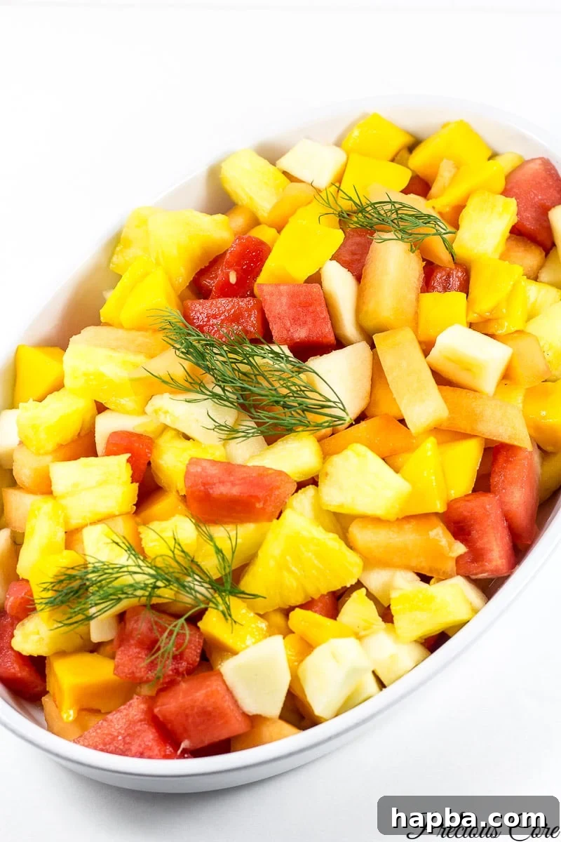 A colorful Cameroonian fruit salad brimming with fresh, diced fruits, elegantly presented in a white serving bowl.