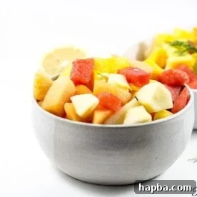 A bowl generously filled with vibrant Cameroonian fruit salad, showcasing a variety of fresh, chopped fruits.