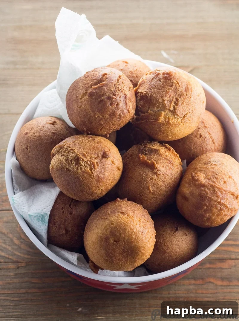 A bowl lined with paper towels, generously filled with golden-brown Cameroonian Beignets Soufflés, perfectly fried and ready to be served.