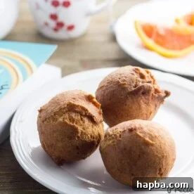 Three perfectly golden Beignets Soufflés artfully arranged on a small plate, ready for tasting.