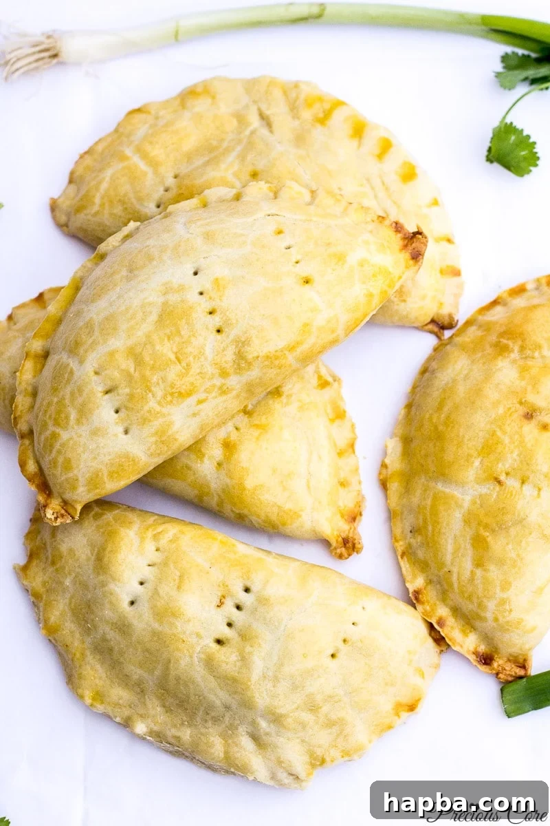 An array of perfectly baked Cameroonian fish pies, elegantly arranged on a pristine white background, showcasing their golden-brown crusts.