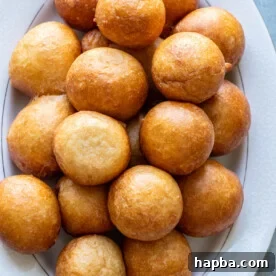 Puff Puff pastries artfully arranged on a white tray, showcasing their perfect round shape and golden hue.