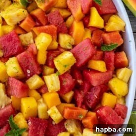 A vibrant and refreshing tropical fruit salad, beautifully arranged in a stylish serving bowl.