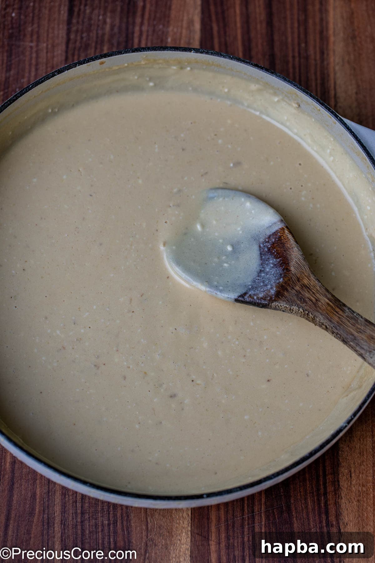 A pot filled with a rich, velvety white cream sauce, perfectly thickened and smooth after the addition of cheeses.