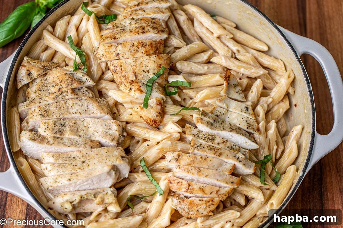 A beautifully presented landscape image of creamy garlic parmesan chicken pasta, generously topped with sliced chicken and vibrant fresh herbs, ready for serving.