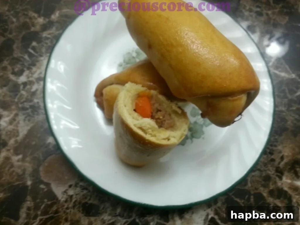 A plate of freshly baked chicken rolls, garnished with herbs, showcasing their golden crust.
