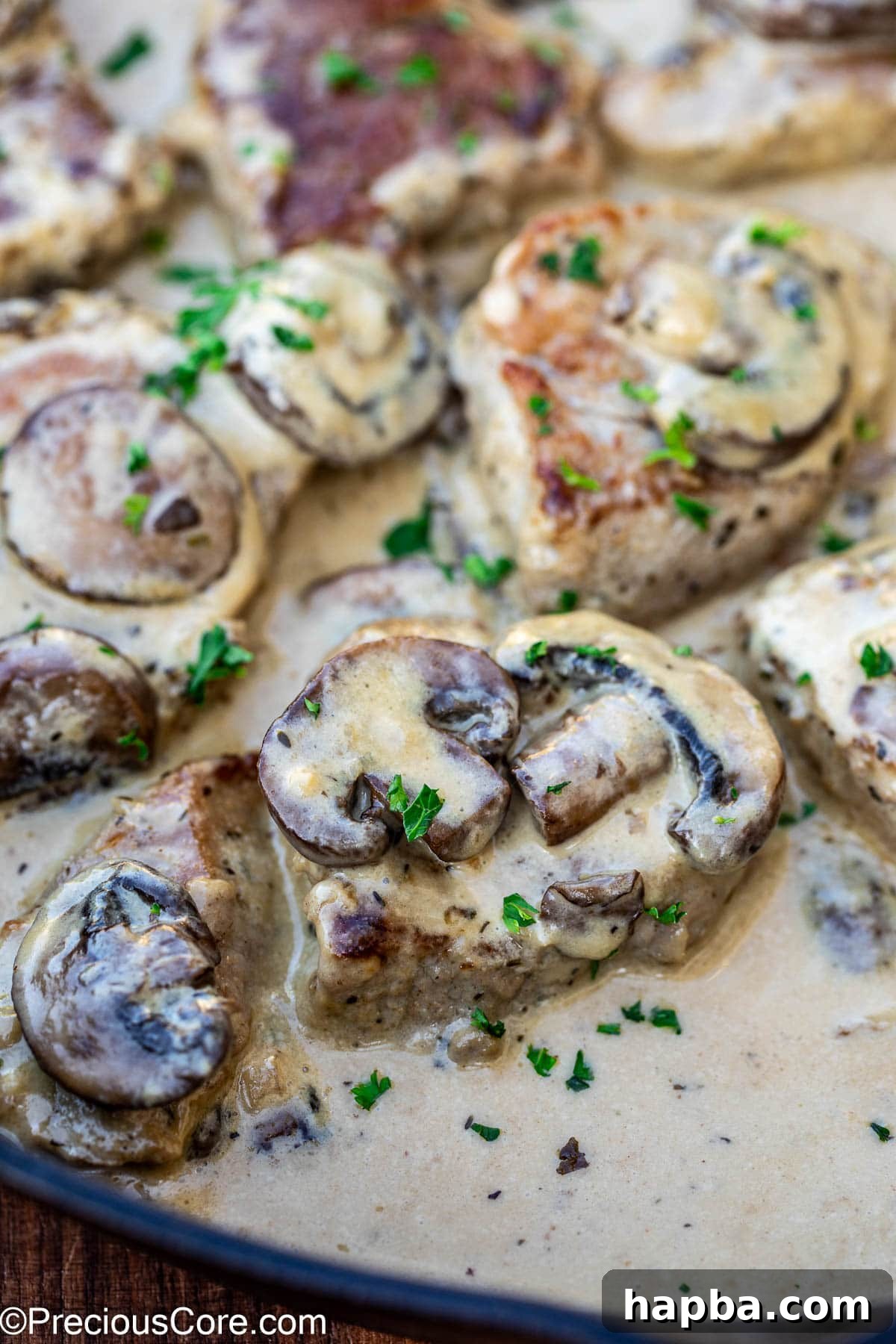 A close-up view of a perfectly cooked pork tenderloin slice generously coated in creamy mushroom sauce.