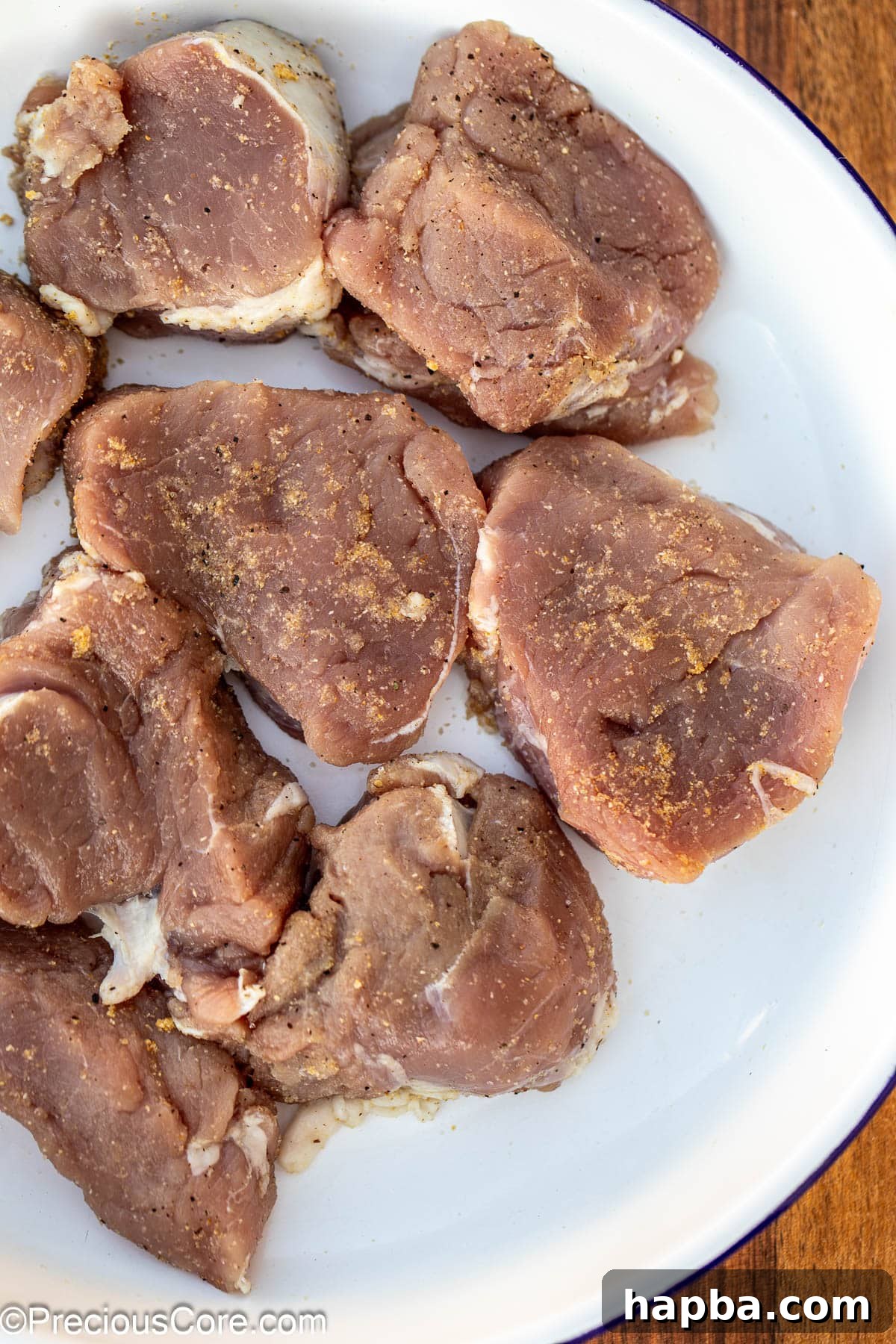 Seasoned pork medallions arranged neatly in a white bowl, ready for searing.