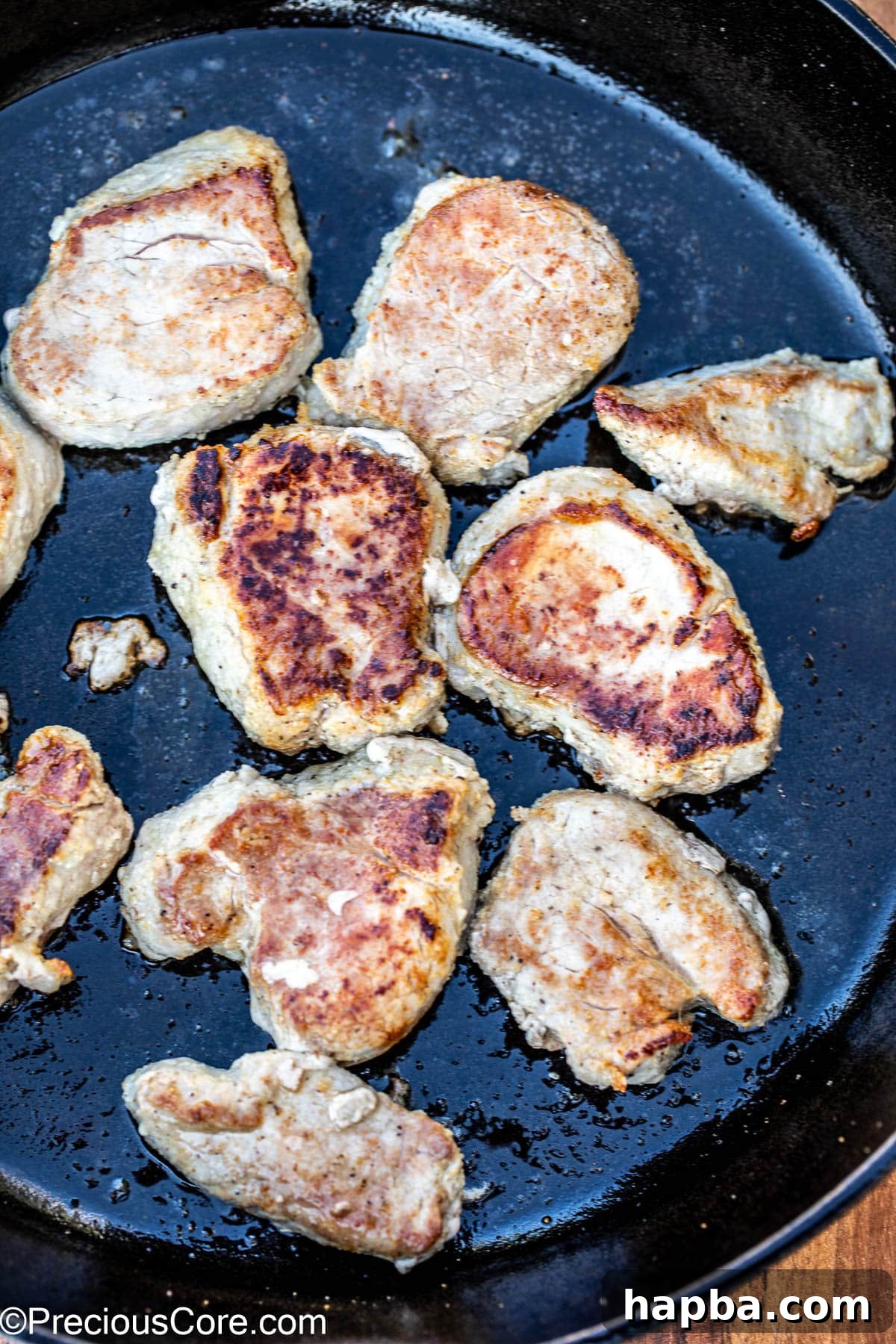 Golden-brown seared pork medallions sizzling in a cast iron skillet.