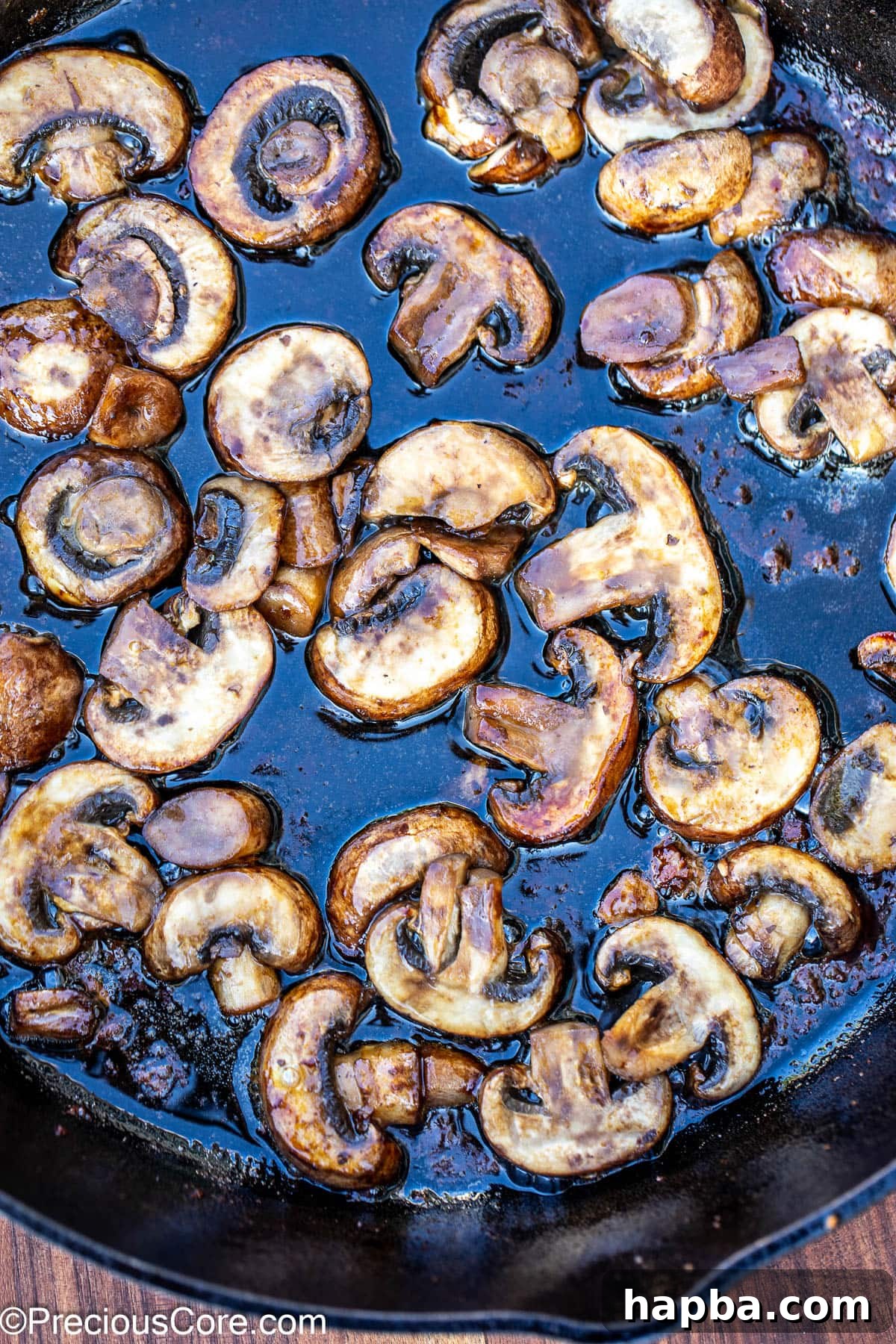 Sliced mushrooms being sautéed until tender and golden in a skillet.