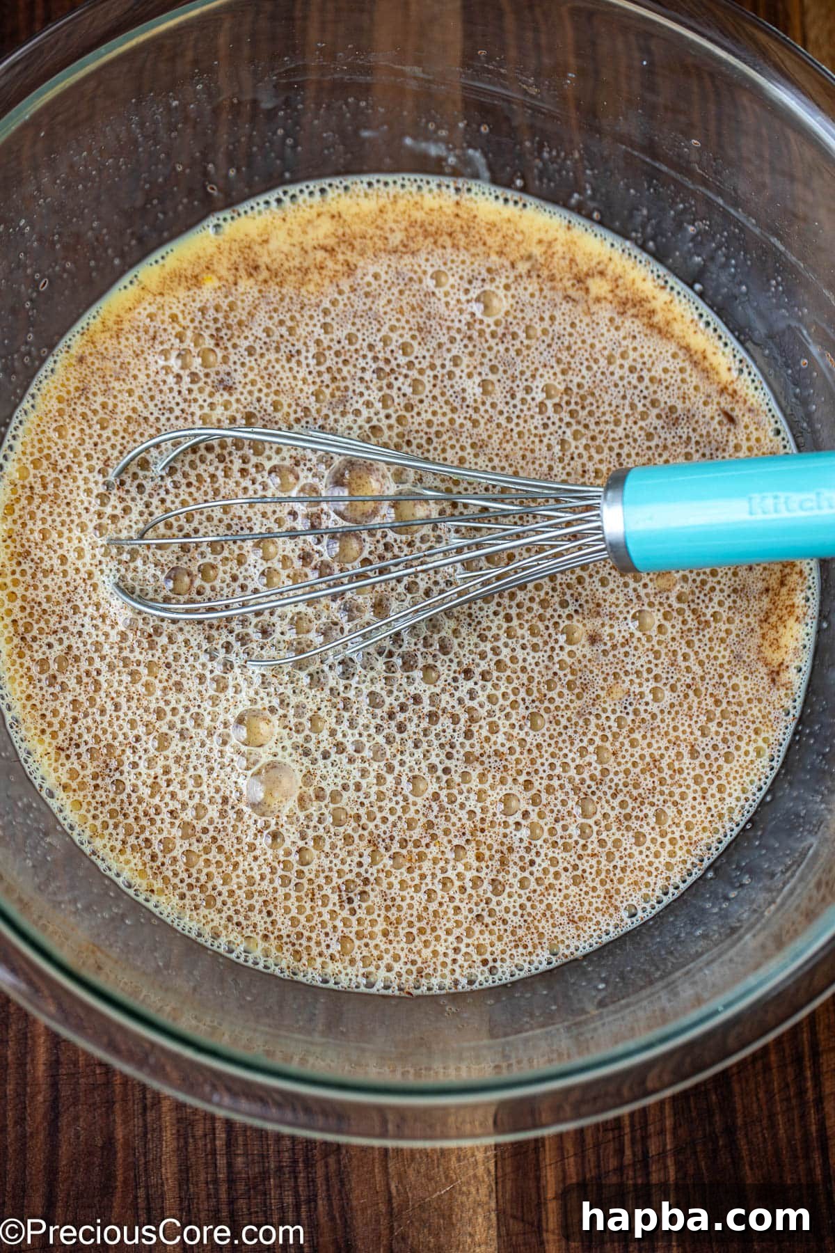 Eggs and milk mixture in a large bowl with a whisk.