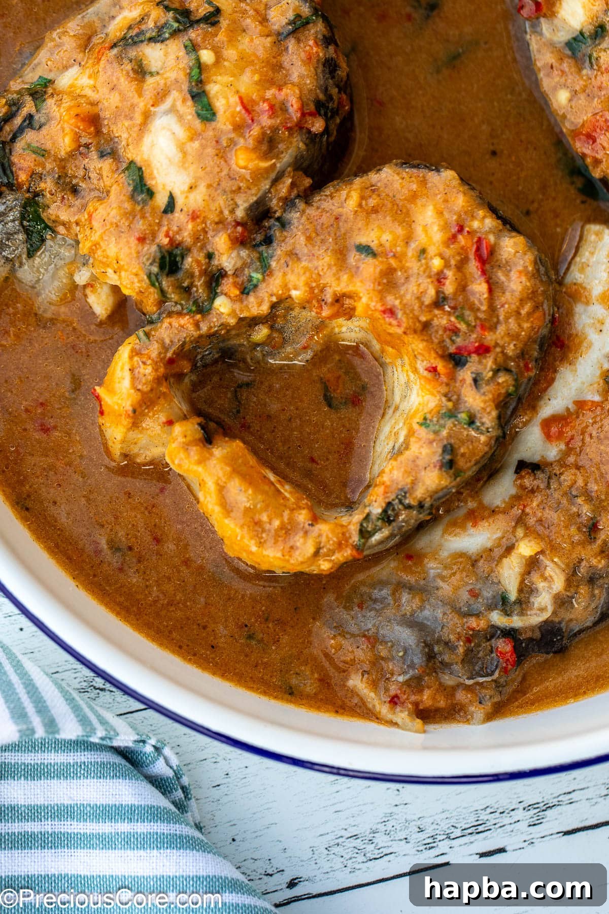 Close-up of fish steaks immersed in a vibrant, spiced broth, ready to be served.