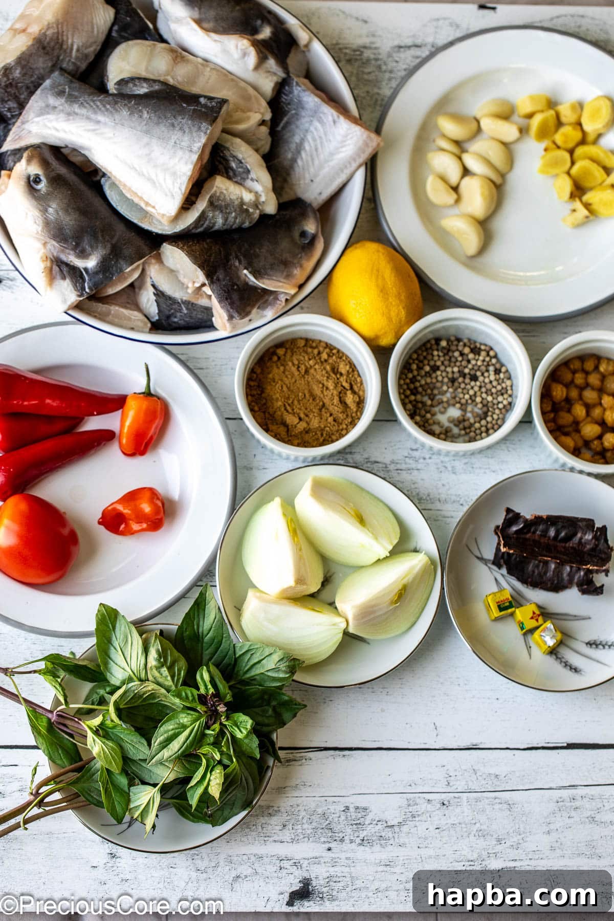 All ingredients for catfish pepper soup laid out neatly on a white surface, showcasing their freshness and variety.