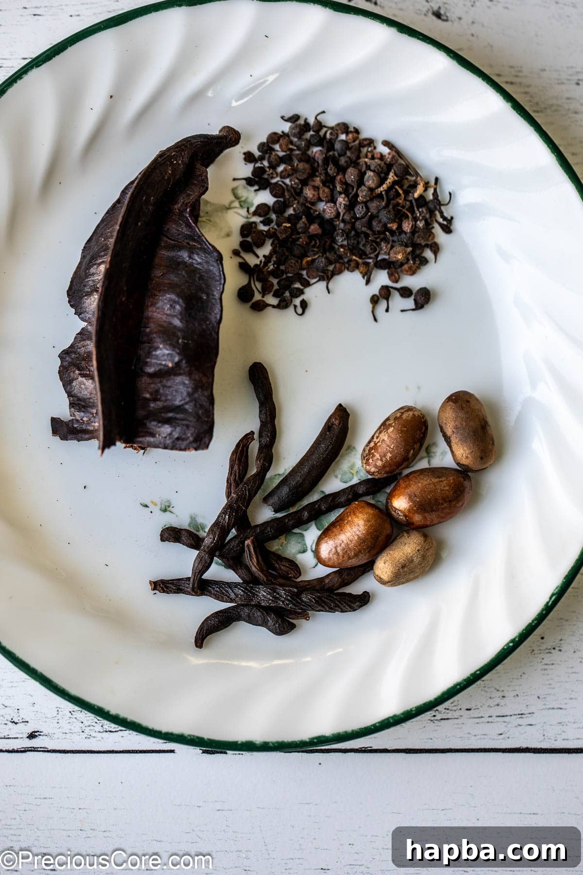 Aidan fruit, African black pepper, negro pepper, and African nutmeg displayed on a white plate, highlighting traditional pepper soup spices.