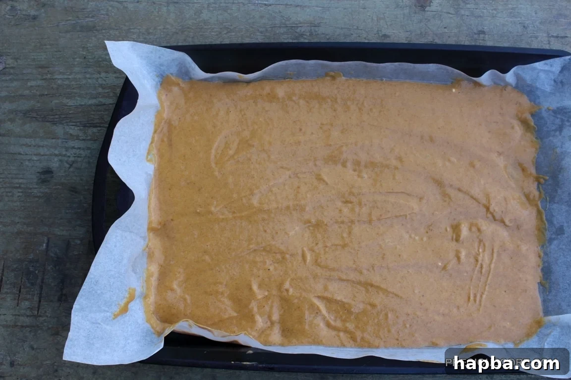 Autumn Spiced Pumpkin Roll 11 Pumpkin roll cake batter spread evenly in a parchment-lined pan.
