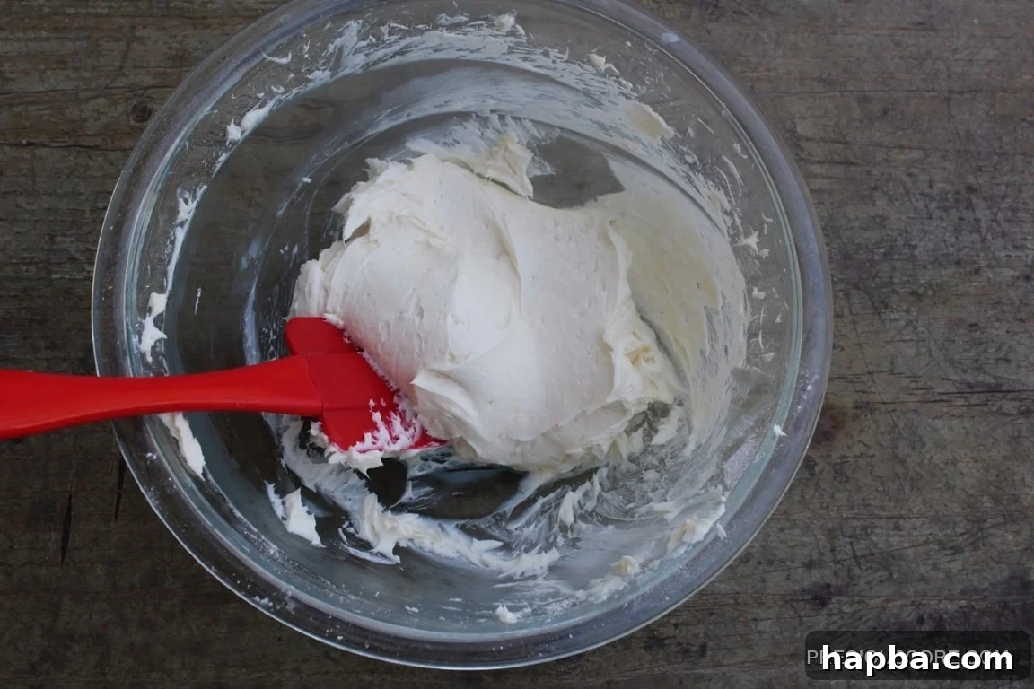 Autumn Spiced Pumpkin Roll 15 A red spatula mixing cream cheese filling ingredients to a smooth consistency.