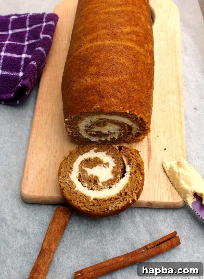 Autumn Spiced Pumpkin Roll 3 A freshly baked pumpkin roll cake resting on a wooden chopping board.