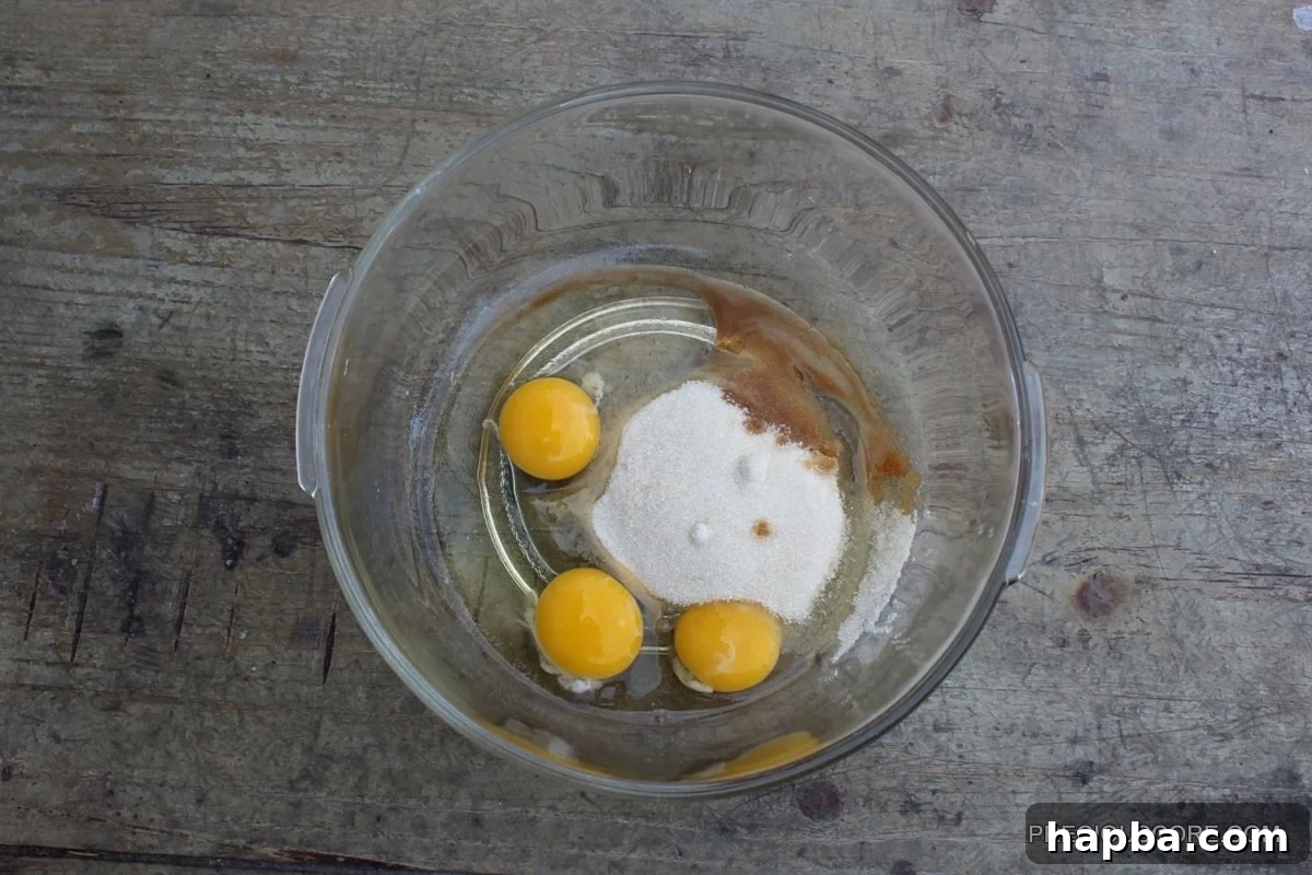 Autumn Spiced Pumpkin Roll 7 Eggs, sugar, and vanilla extract in a glass mixing bowl, before beating.