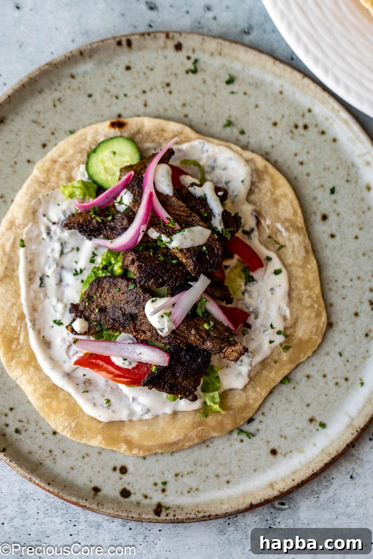 Restaurant-Style Beef Shawarma at Home 9 A delicious flatbread topped with beef shawarma, fresh vegetables, and a generous drizzle of sauce.