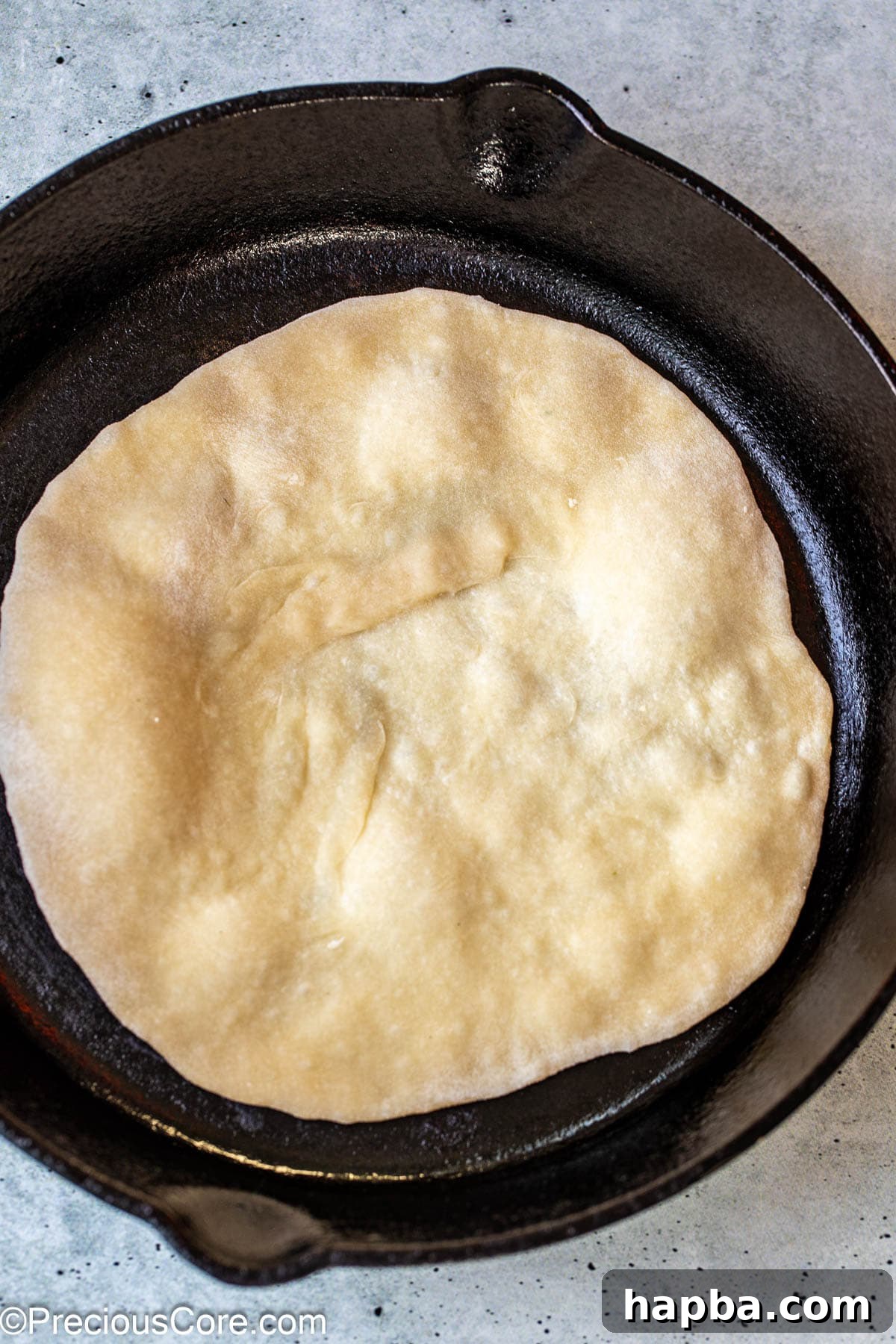Shawarma Flatbread 10 Shawarma bread cooking in a hot skillet, beginning to puff up as it heats.