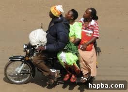 Okada (Motorcycle Taxi) Ride: The Breeze of Freedom An 'Okada' or motorcycle taxi carrying a passenger through a Cameroonian street, illustrating a common and fast mode of transport and the refreshing breeze experienced during the ride.